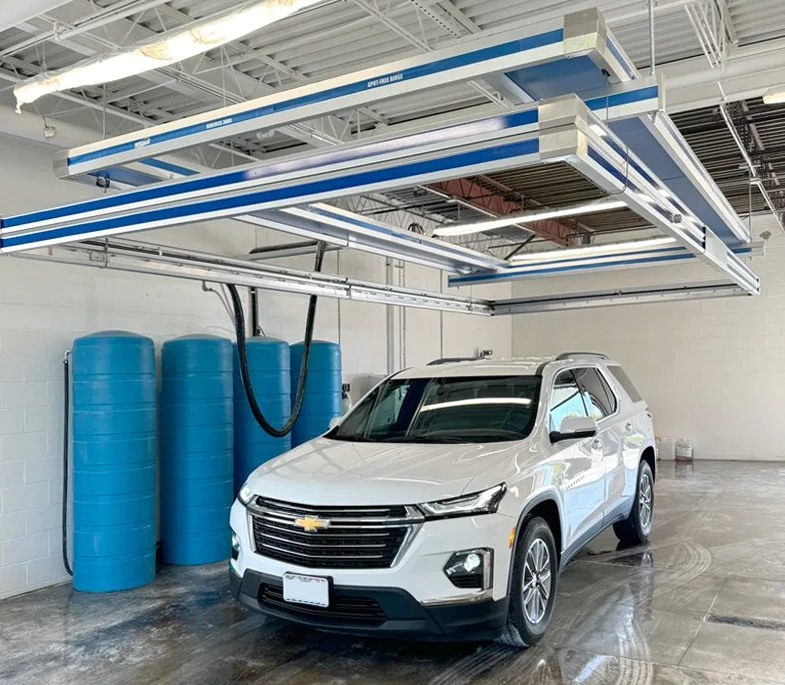 Clean white SUV in a garage bay underneath a Hercules Car Wash System