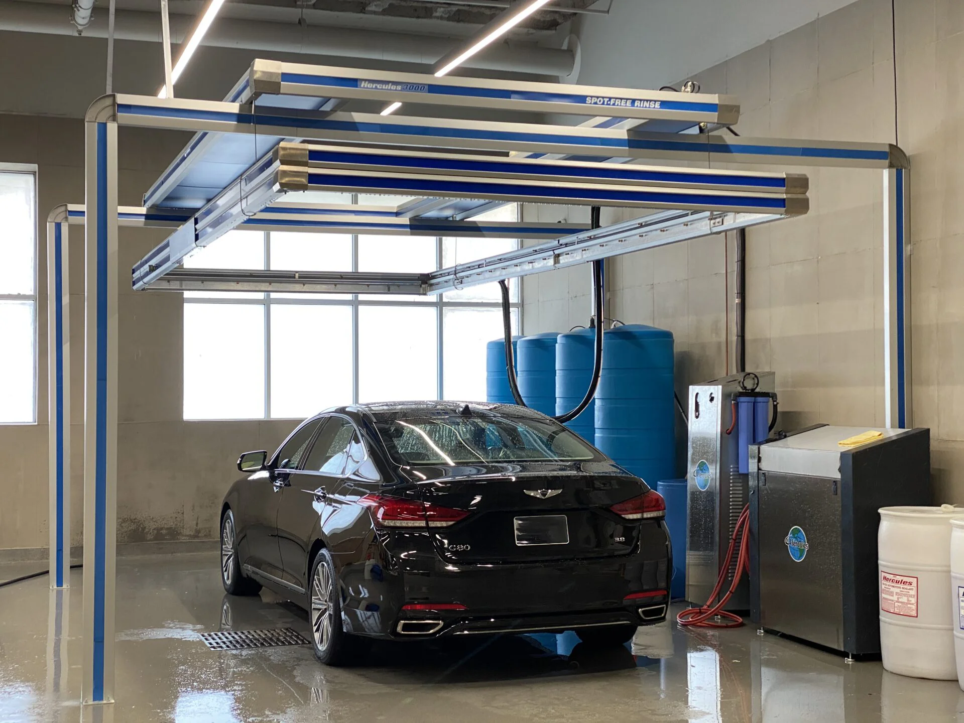 photo of clean black sedan car inside a garage bay underneath a Hercules Car Wash System