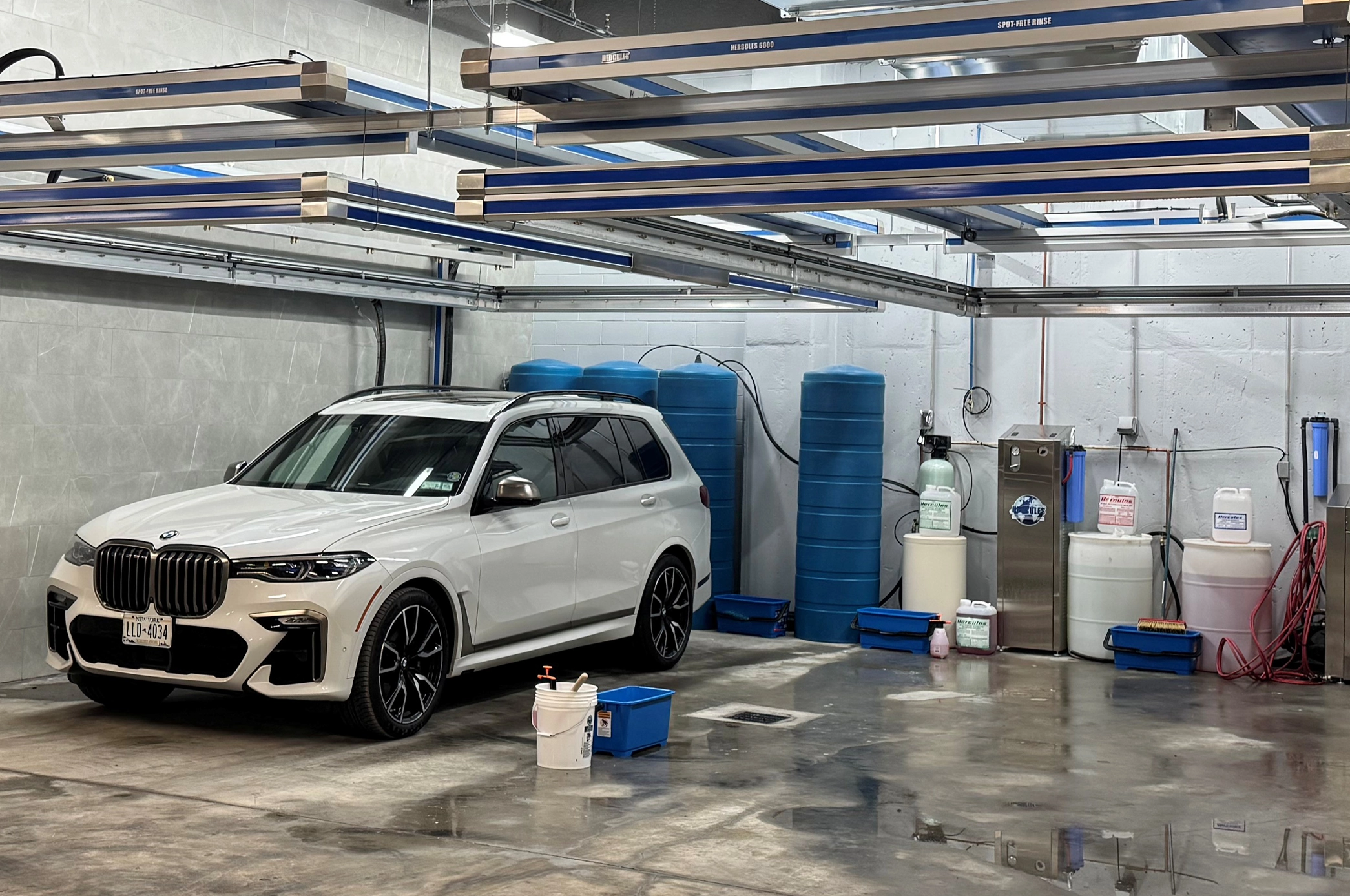 White BMW SUV in a garage bay with 2 Hercules Car wash systems